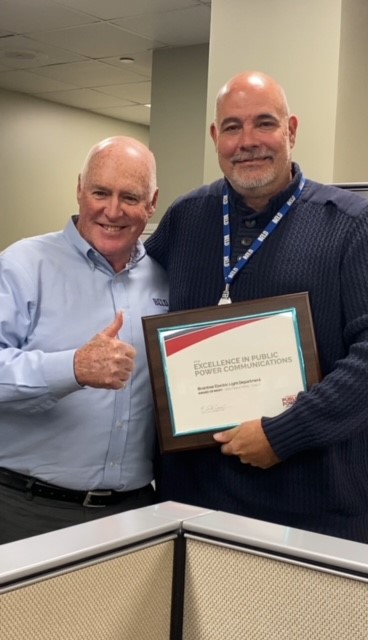 BELD GM, Bill Bottiggi congratulates James Ritchie, BELD Marketing Communications coordinator as he receives the 2023 APPA Excellence in Public Power Communications, Award of Merit.